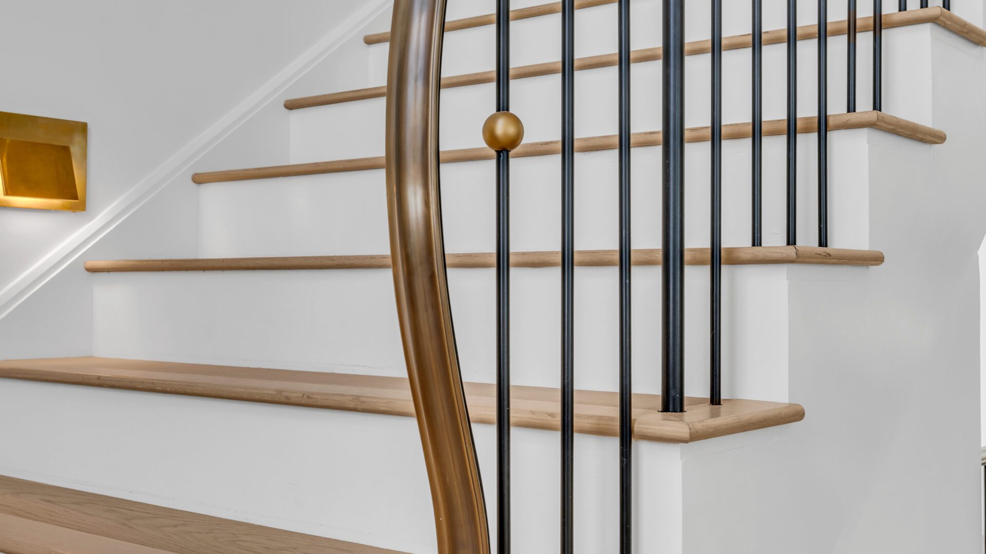 Bronze polished caprail that flows downward and terminates into the floor.