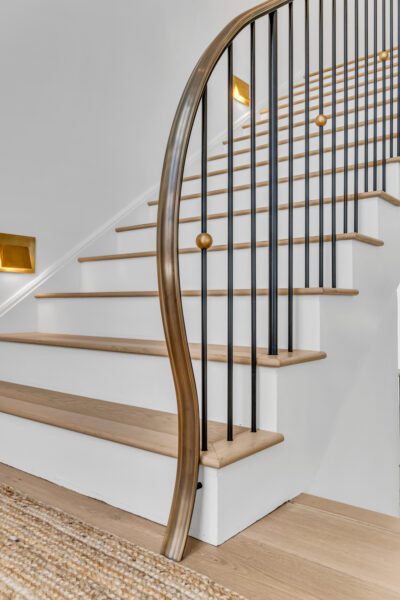 Bronze polished caprail that flows downward and terminates into the floor.