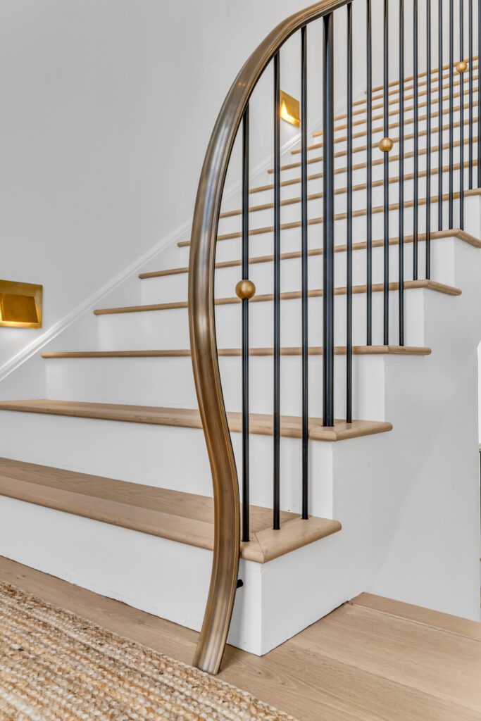 Bronze polished caprail that flows downward and terminates into the floor.