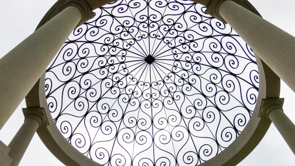 Decorative wrought iron dome featuring intricate scrollwork and symmetrical patterns, showcasing elegant craftsmanship and architectural detail.