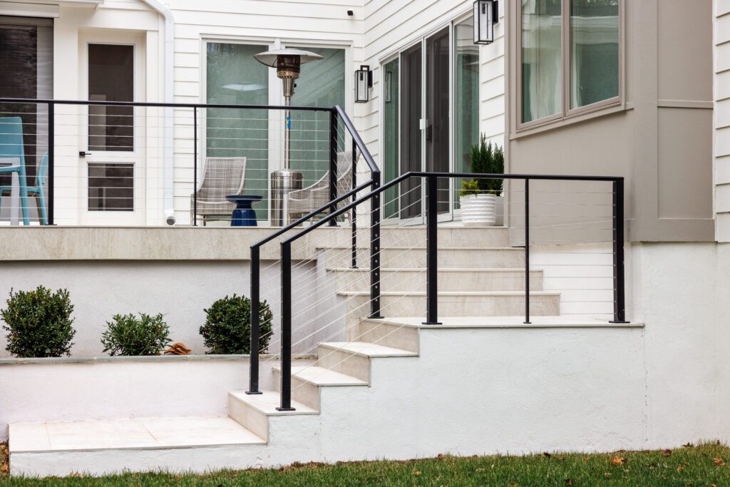 Stainless steel cable railing with black powder coated posts and white concrete treads.