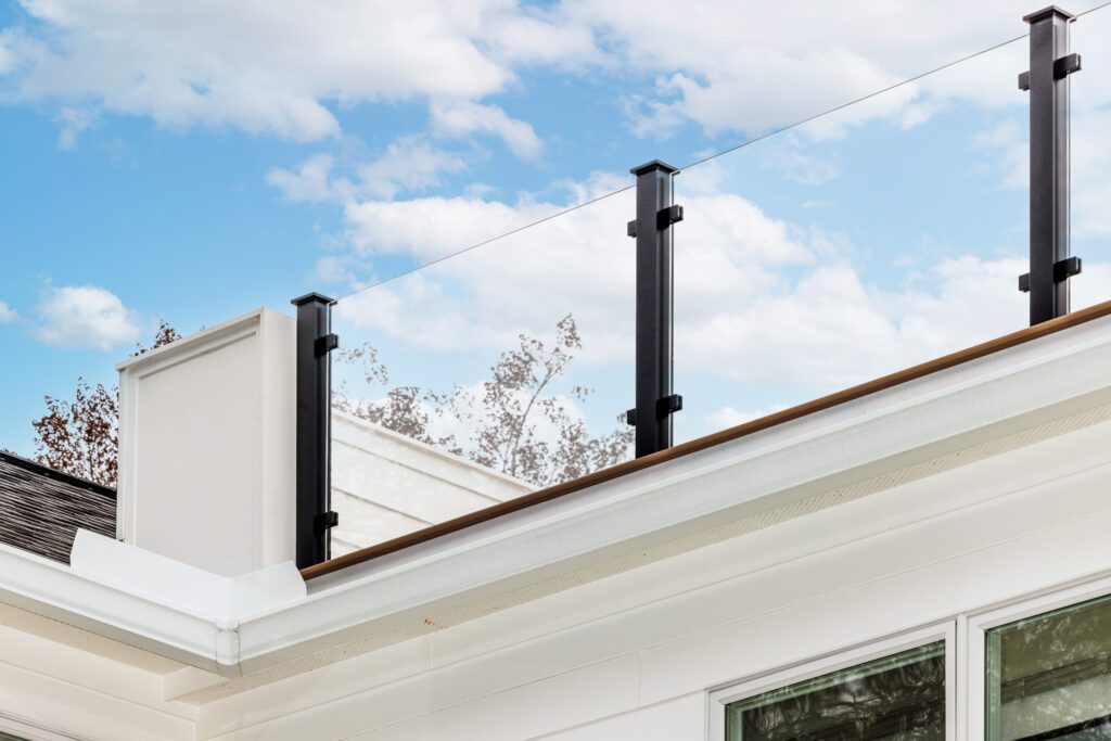 Glass Railing with black posts; back dropped with a bold blue sky.